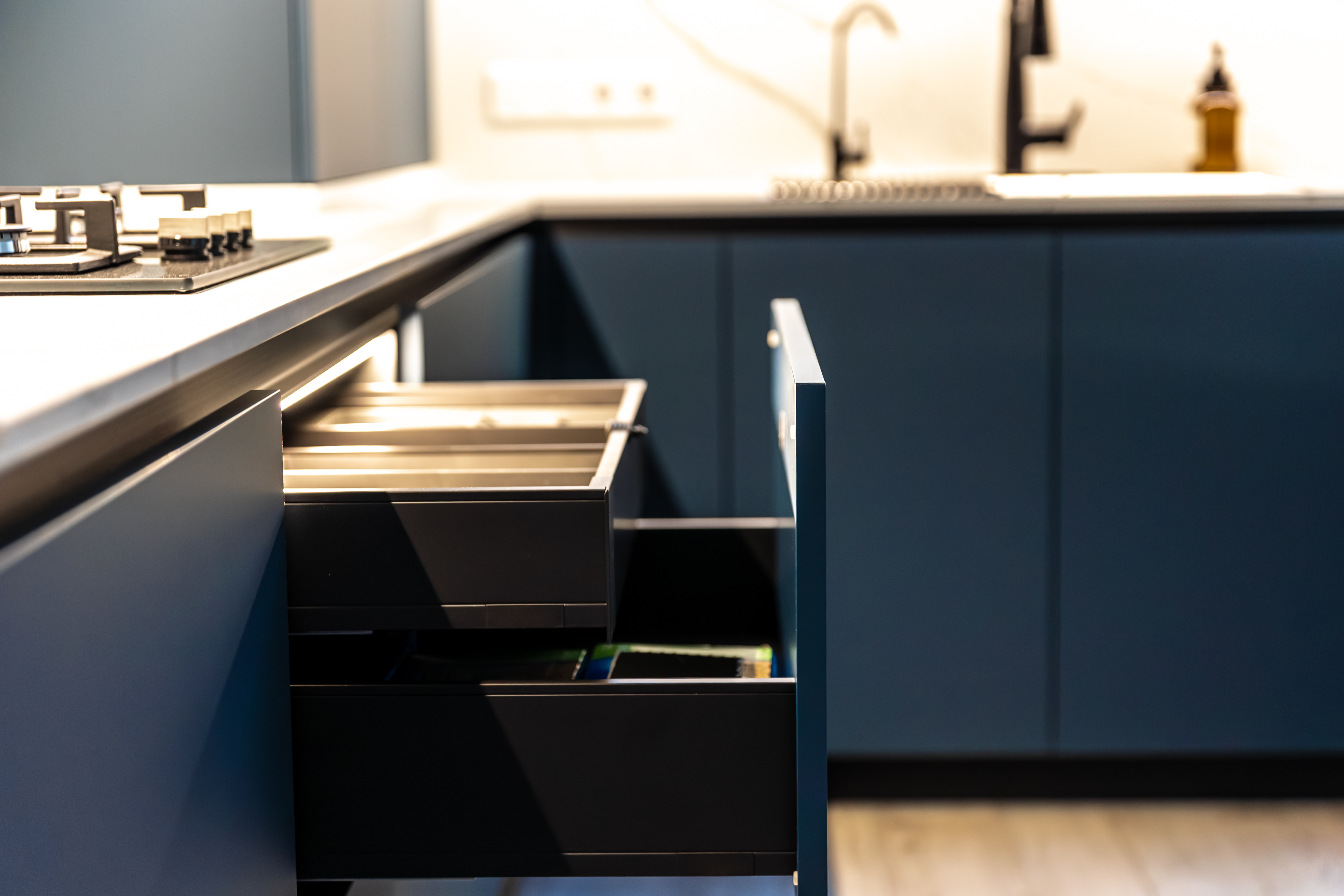 A corner kitchen setup with open drawers, showing a unified area between stovetop and sink. Perfect balance of function and form.
